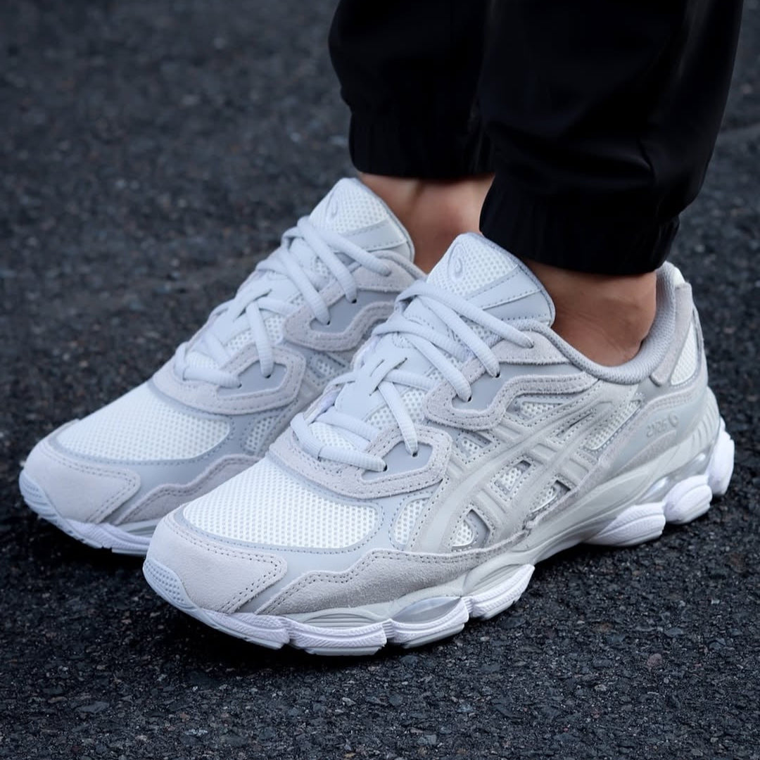 White sneakers worn on a dark asphalt surface