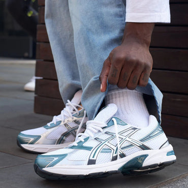 Person wearing white and blue running shoes with a blurred background
