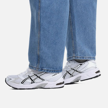 White sneakers with black accents worn with blue jeans on a white background