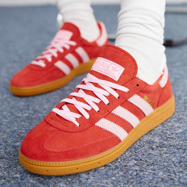 Red sneakers with white stripes worn indoors on a blue carpet
