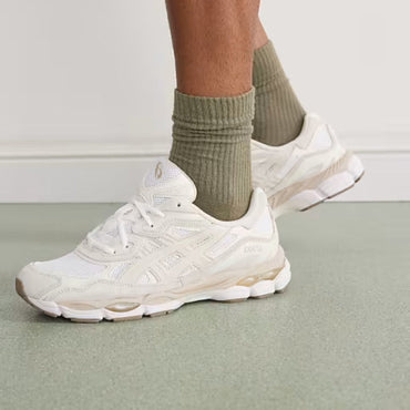 White sneakers worn with green socks on a light gray floor.