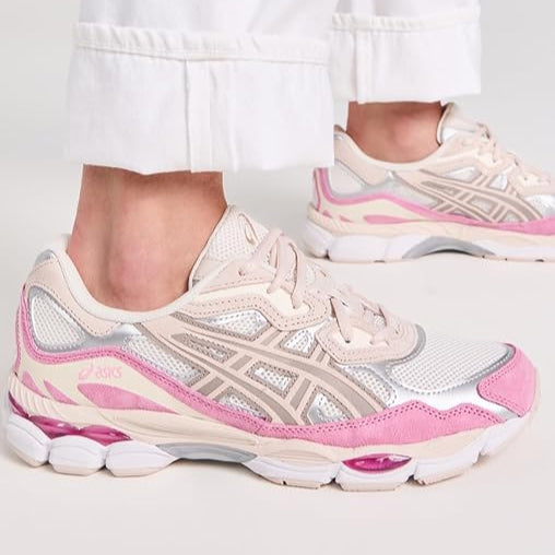 Pink and white sneakers worn with light-colored pants on a plain background