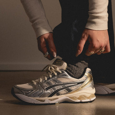 Person adjusting a running shoe with a neutral background
