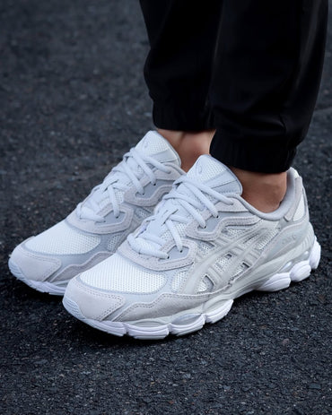 White sneakers worn on a dark asphalt surface