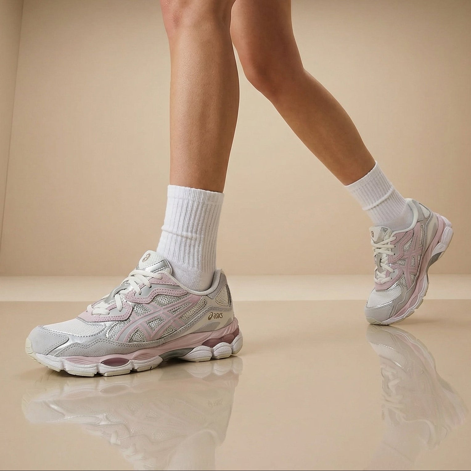 Person wearing light gray sneakers and white socks on a beige floor.
