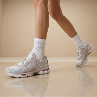 Person wearing light gray sneakers and white socks on a beige floor.