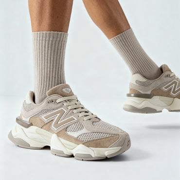 Person wearing beige sneakers and socks on a light gray background