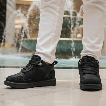 Black boots worn with white pants in a mall setting with water fountain.