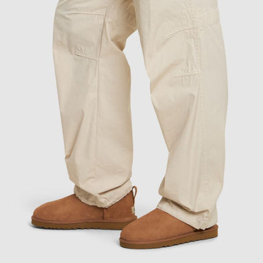 Person wearing beige pants and brown shoes on a white background